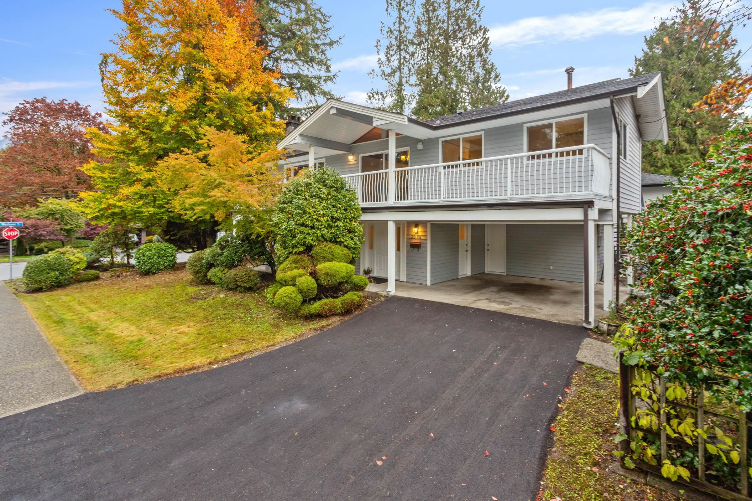 View of front facade with driveway, a carport, and a front lawn